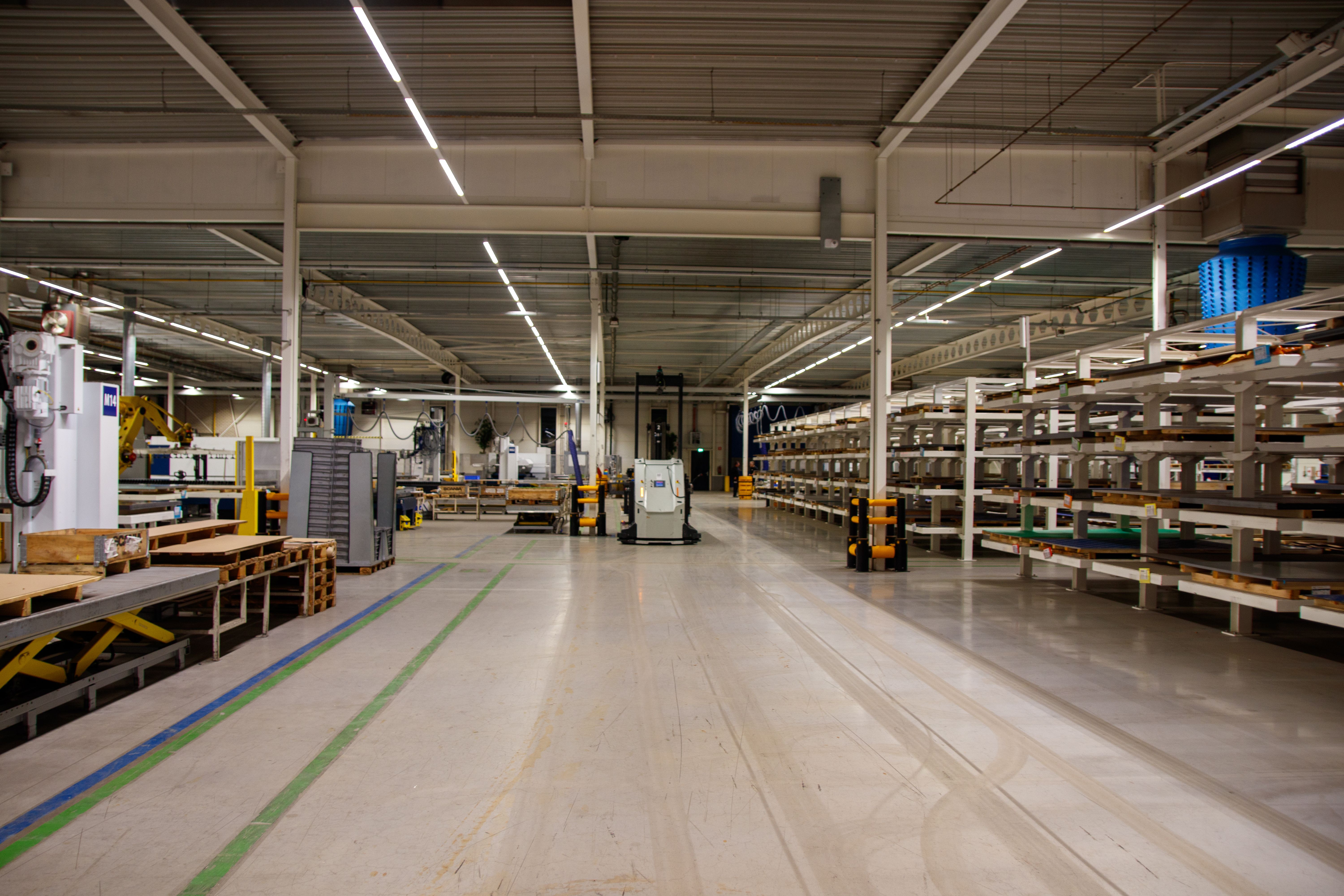 Industrial floor scrubber cleaning a warehouse aisle near loading areas